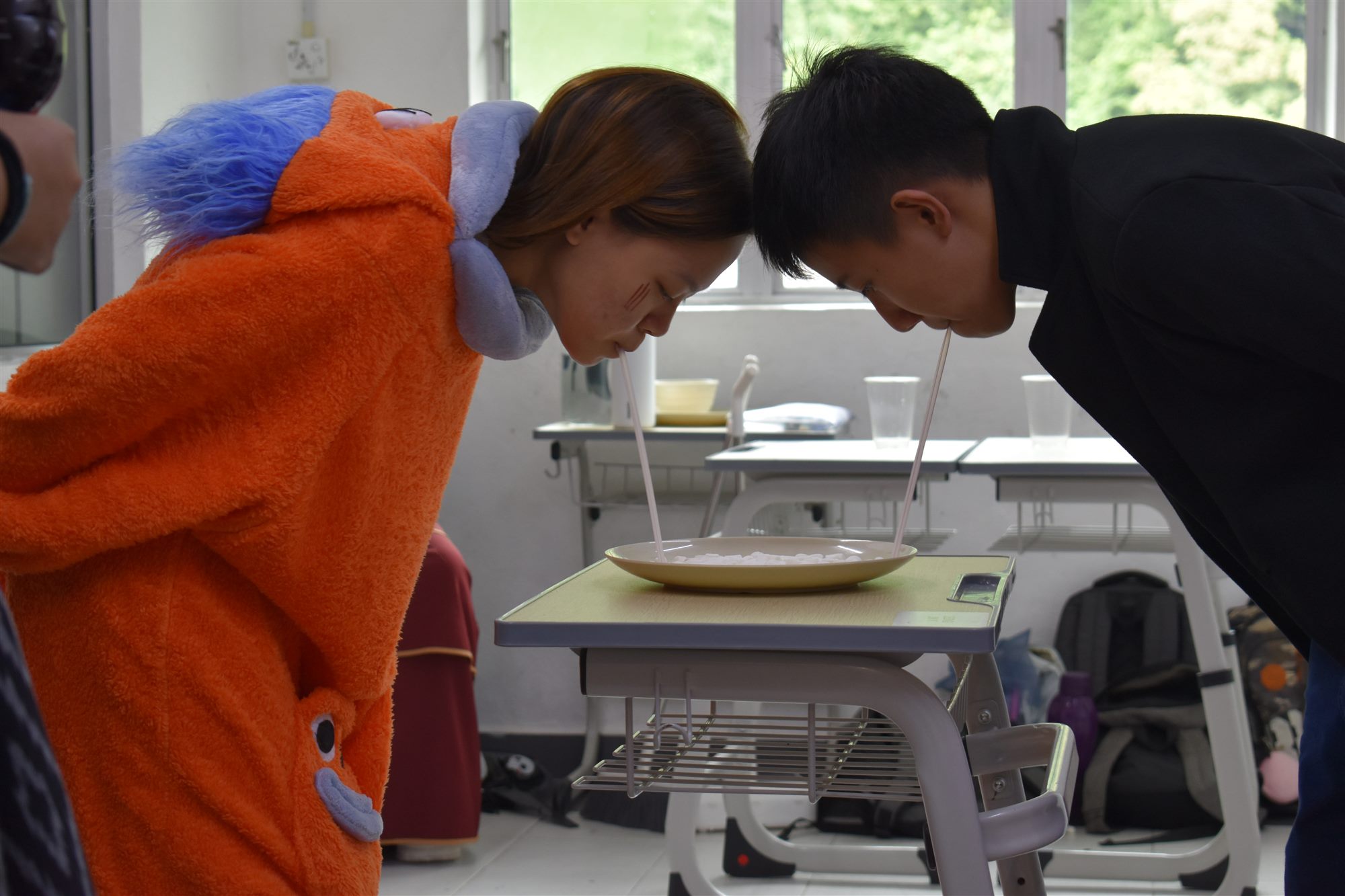 两位同学用长吸管从盘子里吸起棉花糖