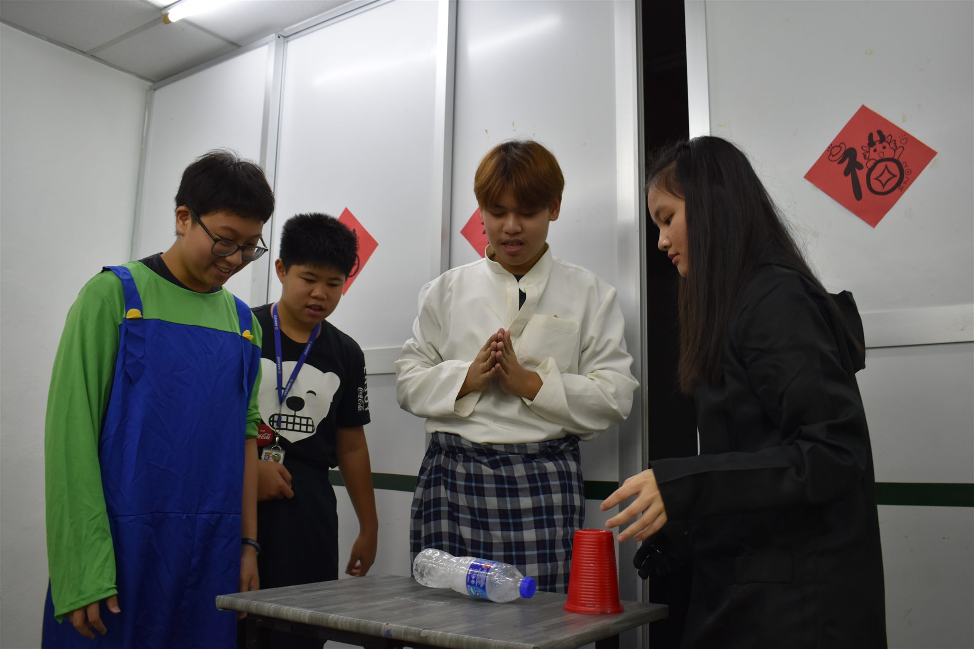 穿着服装的同学们看着队友在幽灵井字棋棋盘上放下红色杯子
